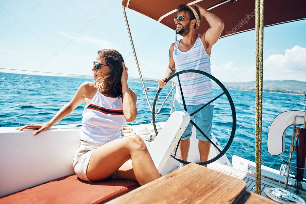 Young man and woman on a sailing boat -Romantic vacation and lux