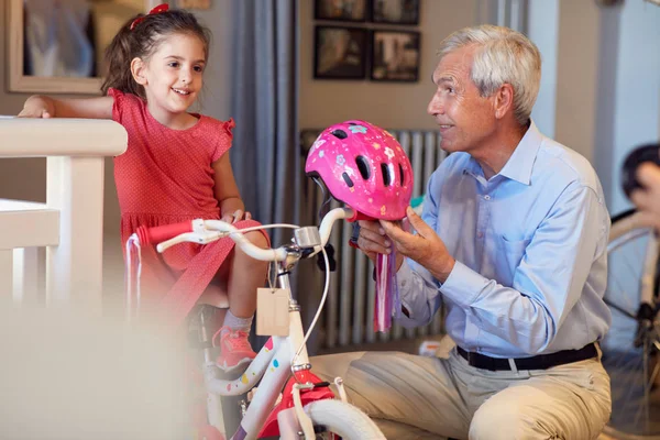 Усміхнений дідусь і дитина дівчина вибирає велосипед у велосипедному магазині — стокове фото