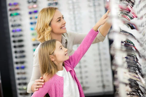 Mãe e menina escolher bela estrutura para óculos — Fotografia de Stock