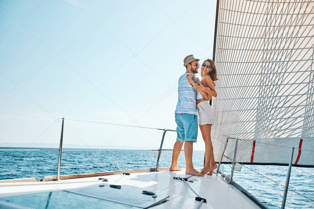 Smiling man and woman traveling on vacation sailing on open sea 
