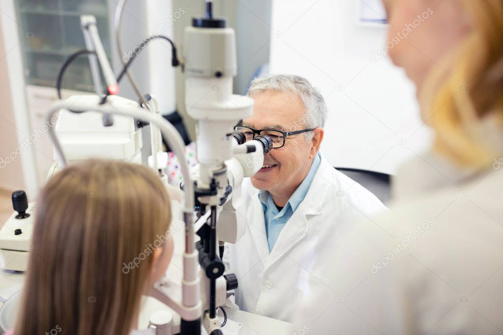 Eye doctor look in special apparatus and check eyesight to child