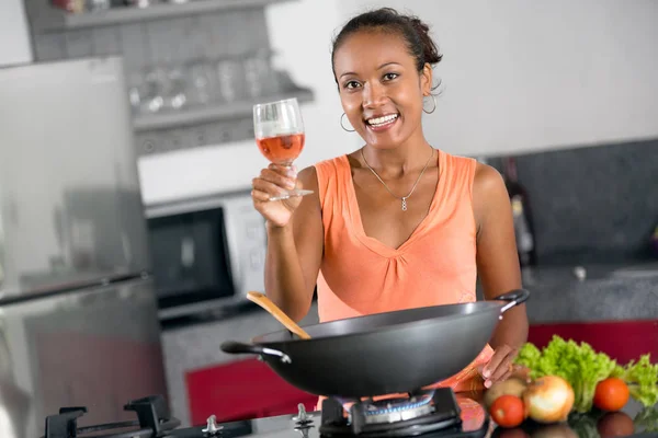 Lachende vrouw staande in de keuken met een glas wijn in haar hand — Stockfoto