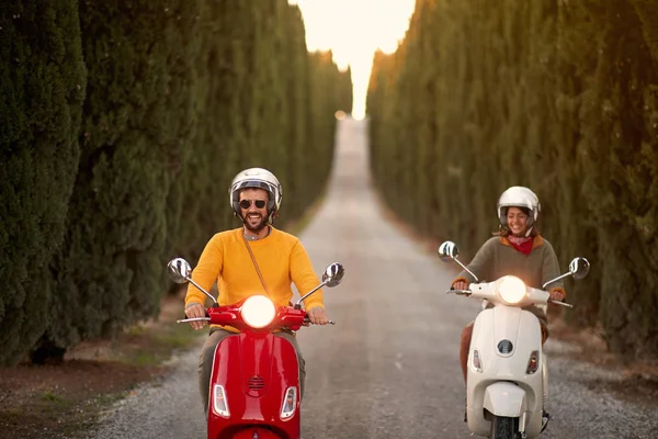 Coppia felice cavalcando uno scooter all'aperto — Foto Stock