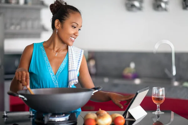 Mulher usando um computador tablet para cozinhar em sua cozinha — Fotografia de Stock