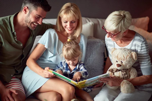 Flicka i familjen ser bild bok — Stockfoto