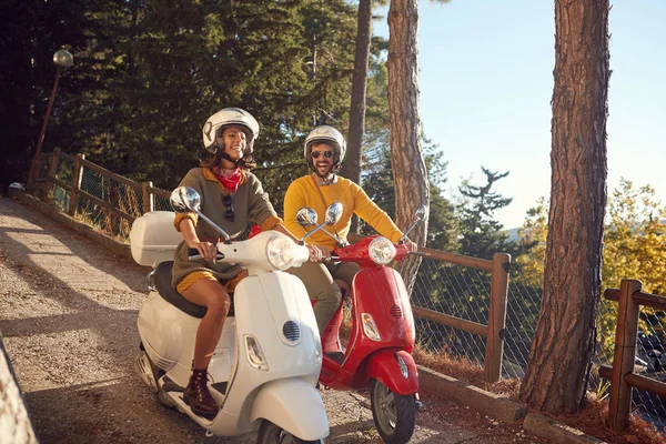 Lächelnde Frauen und Männer mit Motorroller und Blick auf Italien im Urlaub — Stockfoto