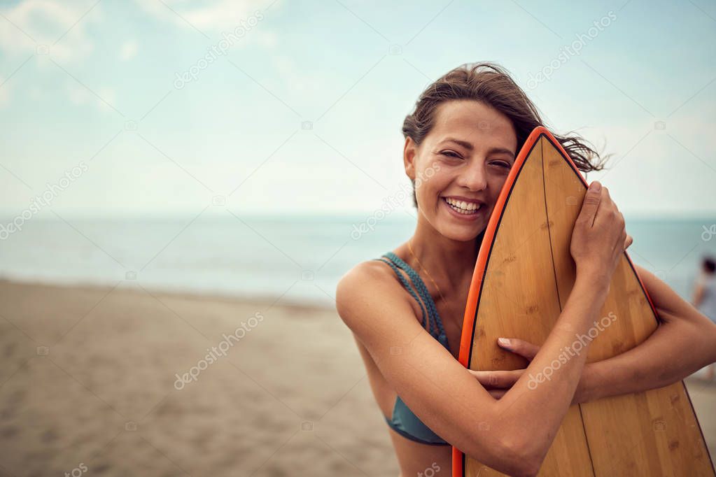 surfer girl posing with her surfboard on the beach