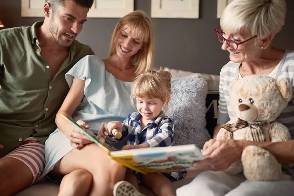 Família procurando livro de fotos com a filha — Fotografia de Stock