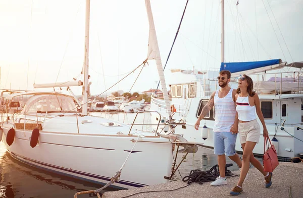 Mann und Frau gehen in der Nähe der Yachten auf dem Dock — Stockfoto