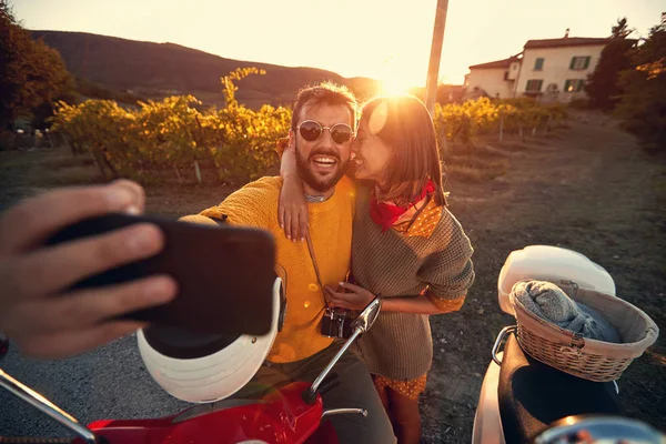 Man and woman on romantic journey on scooter at sunset and take selfie — Stock Photo, Image