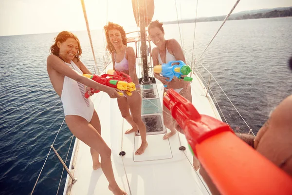 Baráti társaság játszani vitorlás hajón vízipisztollyal — Stock Fotó