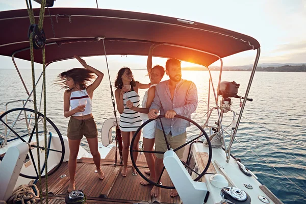 Vrienden genieten van de vakantie op een jacht. Feest op een zeilboot bij zonsondergang — Stockfoto