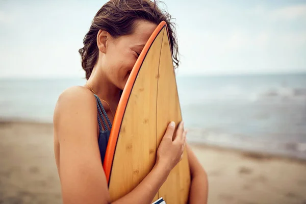 Surfista mulher posando com sua prancha na praia — Fotografia de Stock
