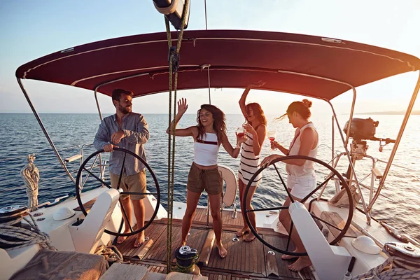 Vrienden zeilen op de luxe boot samen en hebben feest bij zonsondergang. — Stockfoto