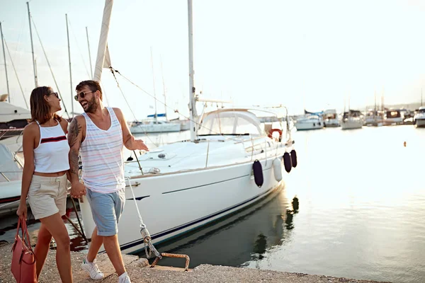 Счастливые молодой человек и женщина прогуливаясь по гавани туристического морского курорта — стоковое фото