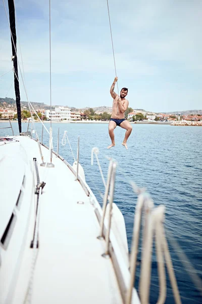 Homem feliz pulando de barco à vela no mar . — Fotografia de Stock