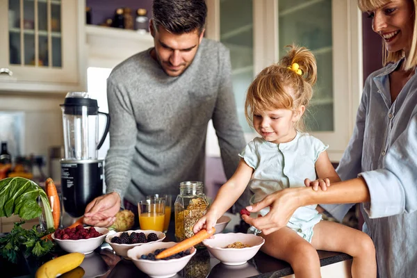 Linda niña con los padres preparando el desayuno — Foto de Stock