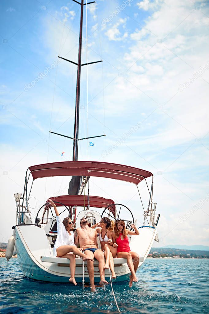 Gruppo di amici che si rilassano sul ponte dello yacht e ridono in vacanza