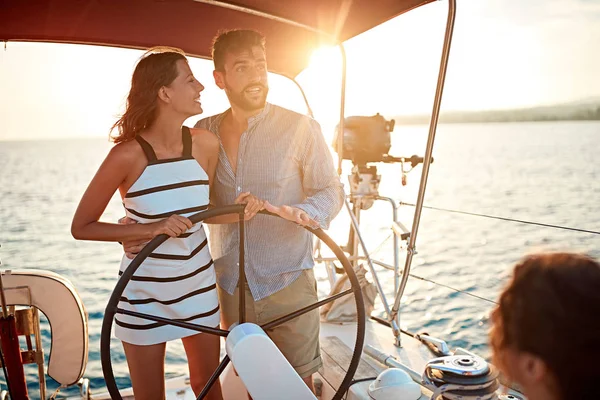 Menina velejando no barco de luxo com o homem e desfrutar ao pôr do sol — Fotografia de Stock