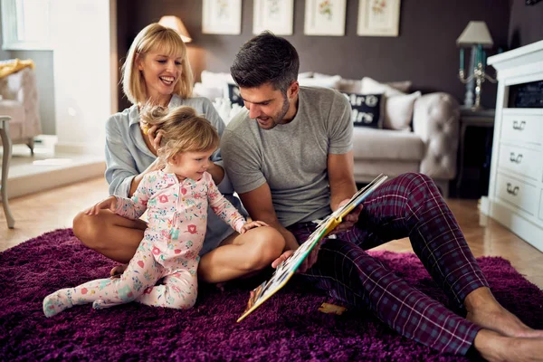 Rodzina z dzieckiem patrząc na książkę zdjęcie — Zdjęcie stockowe
