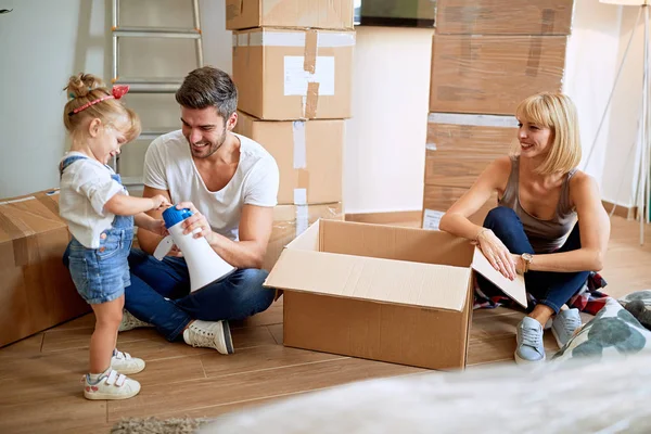 Glückliche Familie zieht in neues Zuhause und packt Kiste aus — Stockfoto