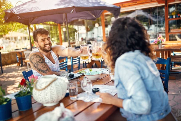 Casal sentado em um restaurante desfrutando de cerveja e conversa — Fotografia de Stock