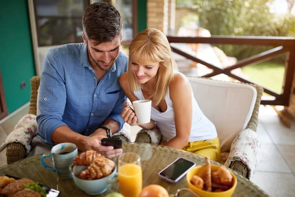 Paar op zoek naar iets op de telefoon op het terras — Stockfoto