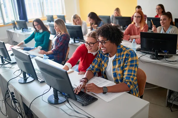 Studenten zitten samen aan tafel met computer in de klas — Stockfoto