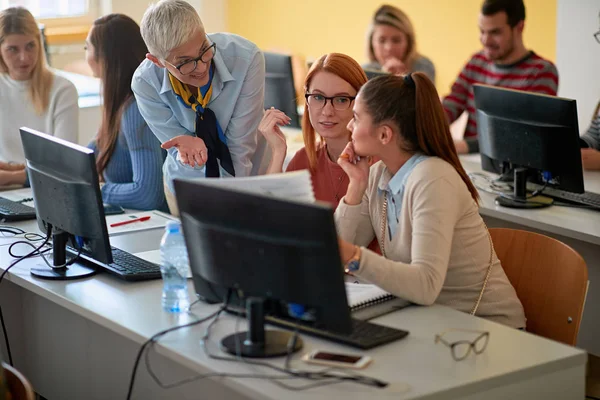 Преподаватель с девочками, работающими в компьютерном классе по университету — стоковое фото