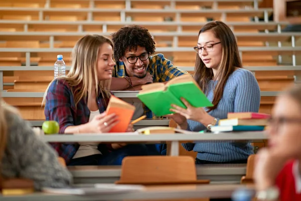 Estudantes sorrindo discussão e escrita juntos na faculdade — Fotografia de Stock