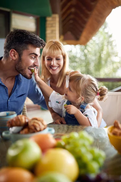 Cute little girl feeds her father with grape — Stock Photo, Image