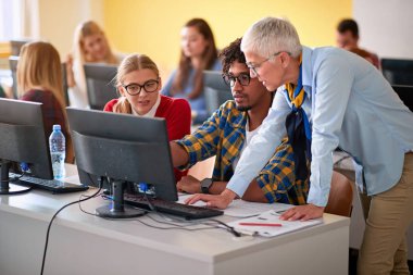 Bilgisayar sınıfında öğretim üyesi, üniversite öğrencisine yardımcı