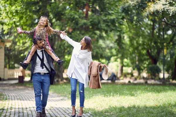 Родители прогуливаясь с там маленькая школьница через парк — стоковое фото