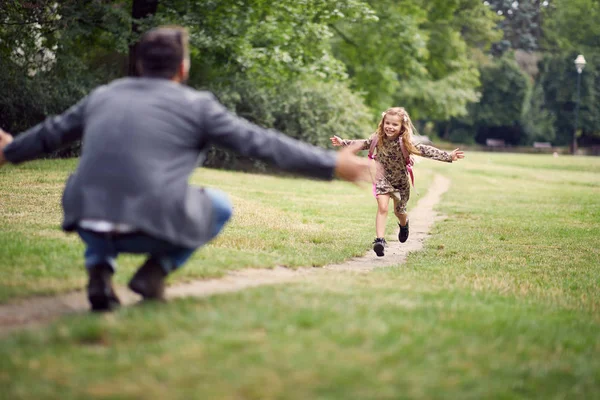 Schoolgirl kör för att krama sin far efter första skoldagen — Stockfoto