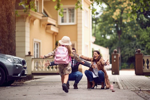 Moeder en vader wachten hun schoolmeisje op na de les op de eerste dag — Stockfoto