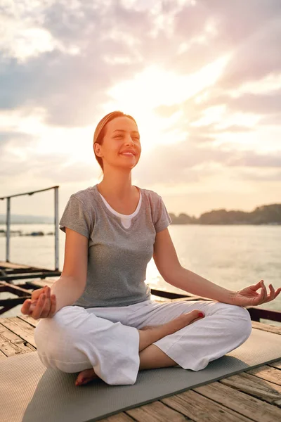 Mujer en muelle en pose de yoga — Foto de Stock