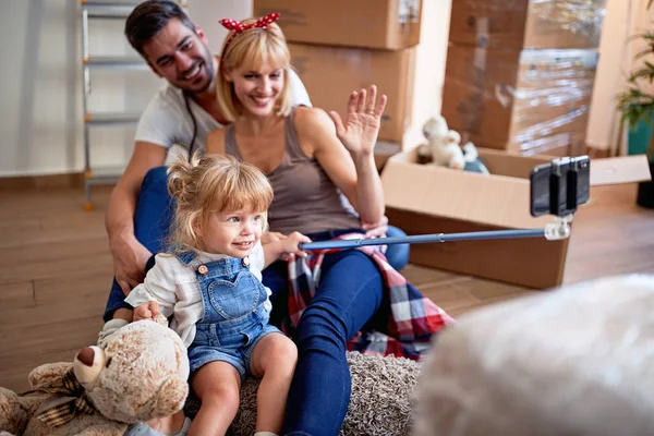 Parents with a toddler girl taking selfie after moving into new — Stock Photo, Image