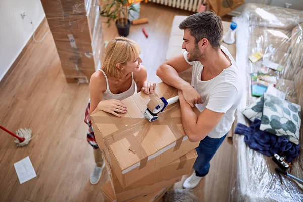 Happy woman packing box with man. Moving in new house. — Stock Photo, Image