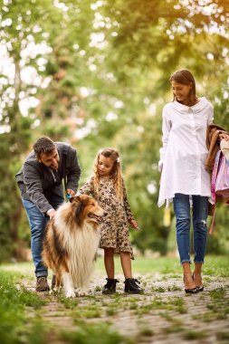 Anne ve baba kızları ile parkta köpek ile eğleniyor