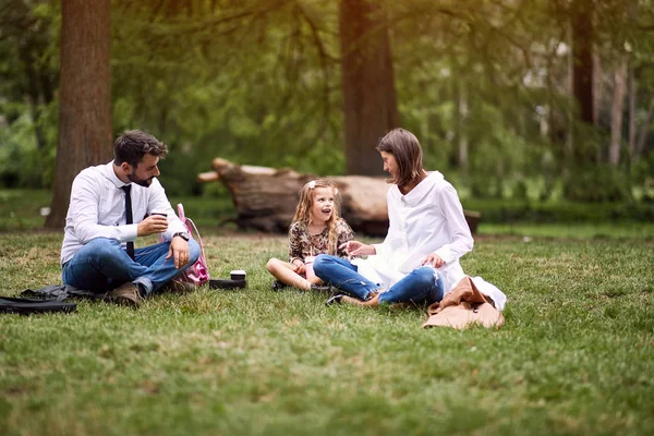 Aile işten sonra ve okul oturma ve parkta dinlenme — Stok fotoğraf