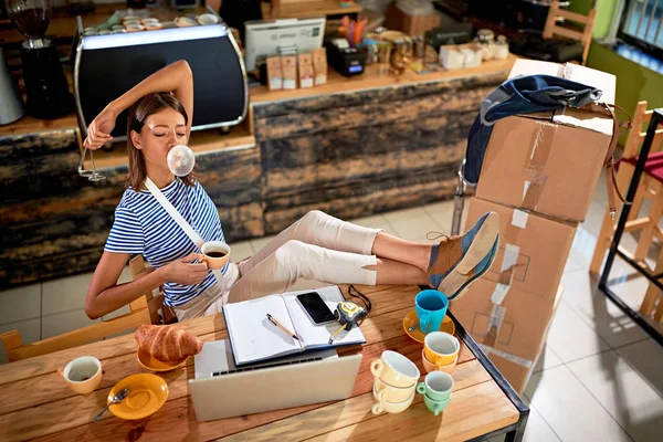 Rilassato proprietario donna in mensa con un computer portatile hanno brea — Foto Stock