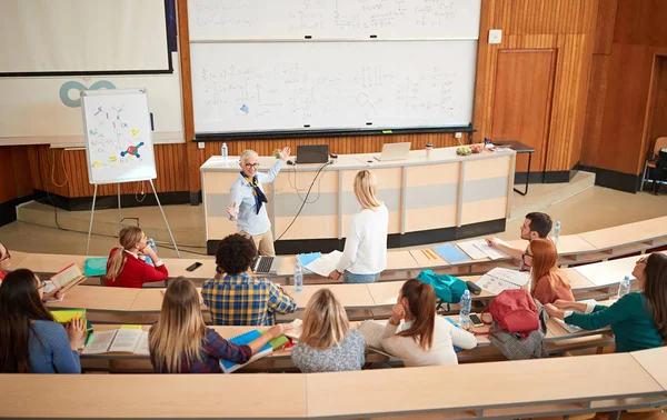 Groep studenten luisteren naar professor in de klas — Stockfoto