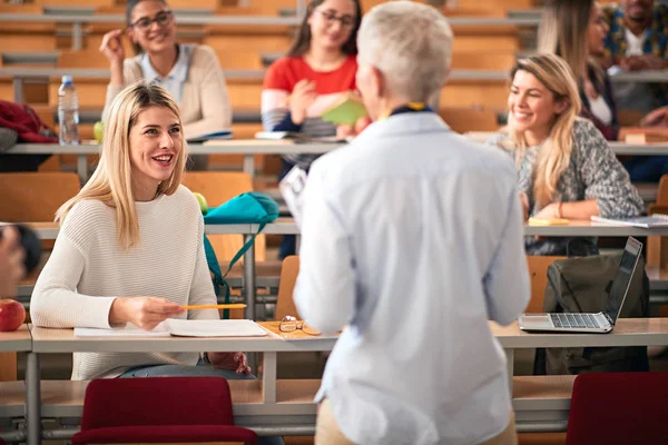 Young girl listens to a teacher in a classroom — Stock Photo, Image