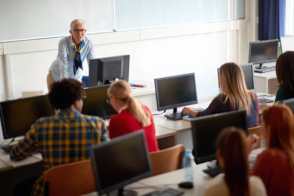 Leende föreläsare på klass med elever i föreläsningssalen — Stockfoto