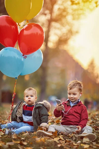 Niños jugando con globos y teléfonos inteligentes al aire libre — Foto de Stock