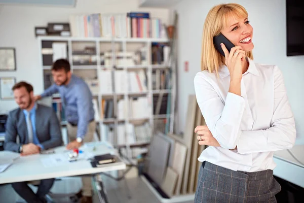 Lachende vrouw staande in Business Office en gebruik telefoon — Stockfoto