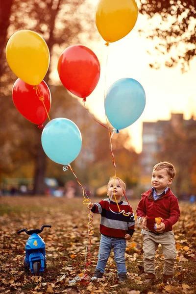 Niños felices jugando juntos en el parque de otoño con globo — Foto de Stock