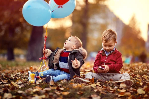 Kinderen spelen met ballonnen en smartphone buiten — Stockfoto