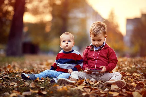 Niño feliz escuchar música en el teléfono inteligente en el parque — Foto de Stock