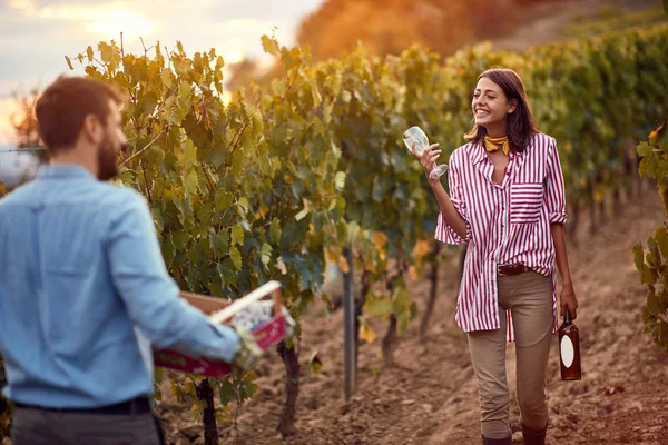 Happy farming woman with wine on vineyard